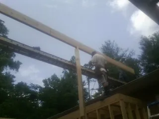 Carpenter setting a ridge beam over a new addition frame — Ice Dam Removal by Roofing Brothers in Commerce Township