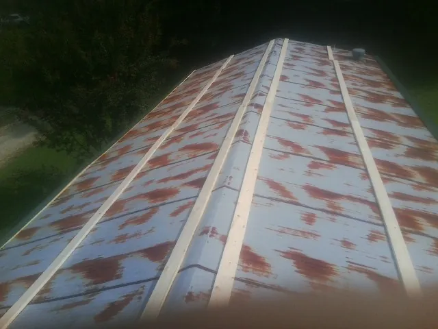 Rusted metal roof panels with new wood purlins before replacement — Storm Damage Roof Repair in Commerce Township by Roofing Brothers
