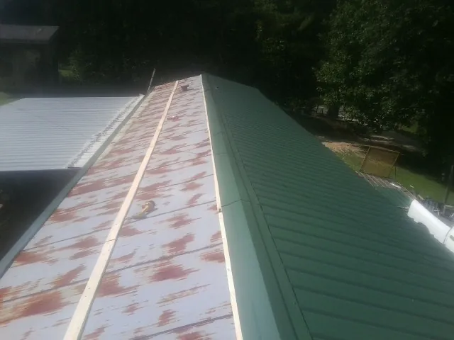Old rusted panels beside newly installed green metal roofing — Wind Damage Roof Repair by Roofing Brothers in Commerce Township