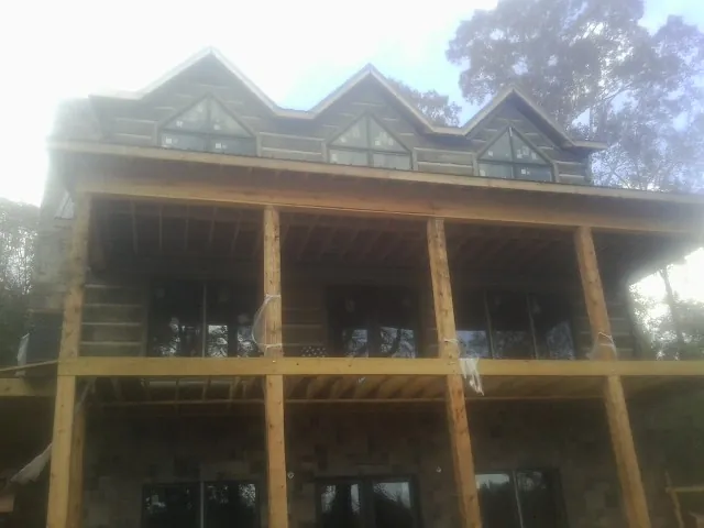 Dormers and porch framing on a large log home under construction — Roof Coating work by our crew in Commerce Township