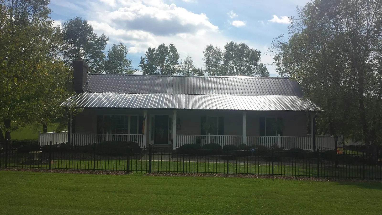 Gray metal roof on a brick ranch with a full width front porch — Gutter Guard Installation work by our crew in Commerce Township