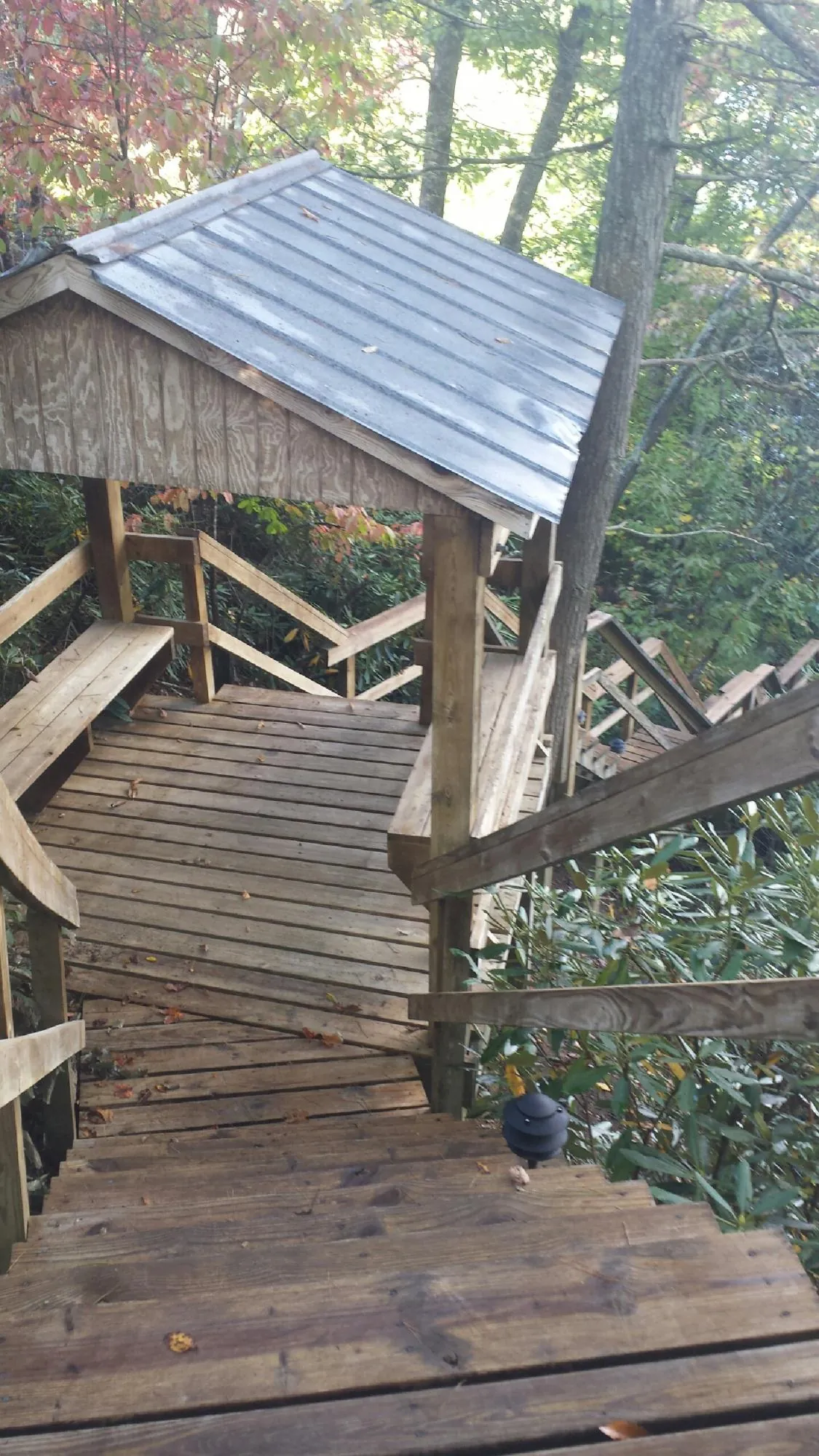 Metal roofed shelter over wooden steps on a wooded walkway — Skylight Repair & Installation work by our crew in Commerce Township