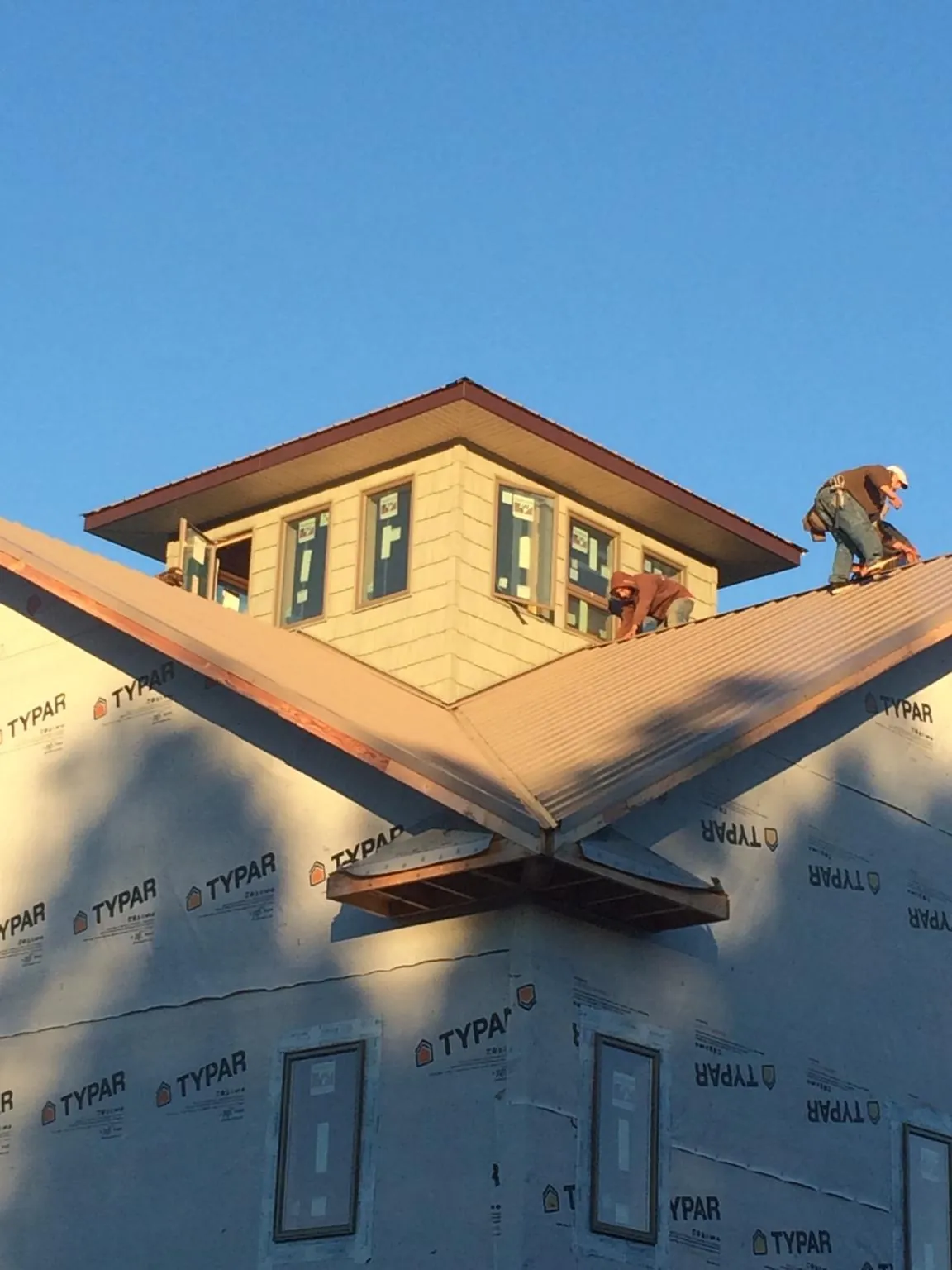 Roofers working around a rooftop cupola on a new metal roof at sunset — Roof Waterproofing in Commerce Township by Roofing Brothers